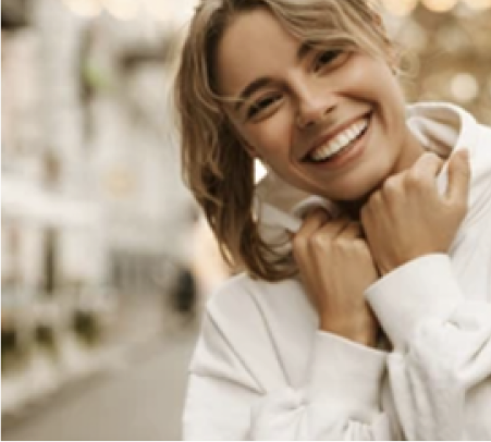 Una mujer con un suéter blanco que sonríe cálidamente.